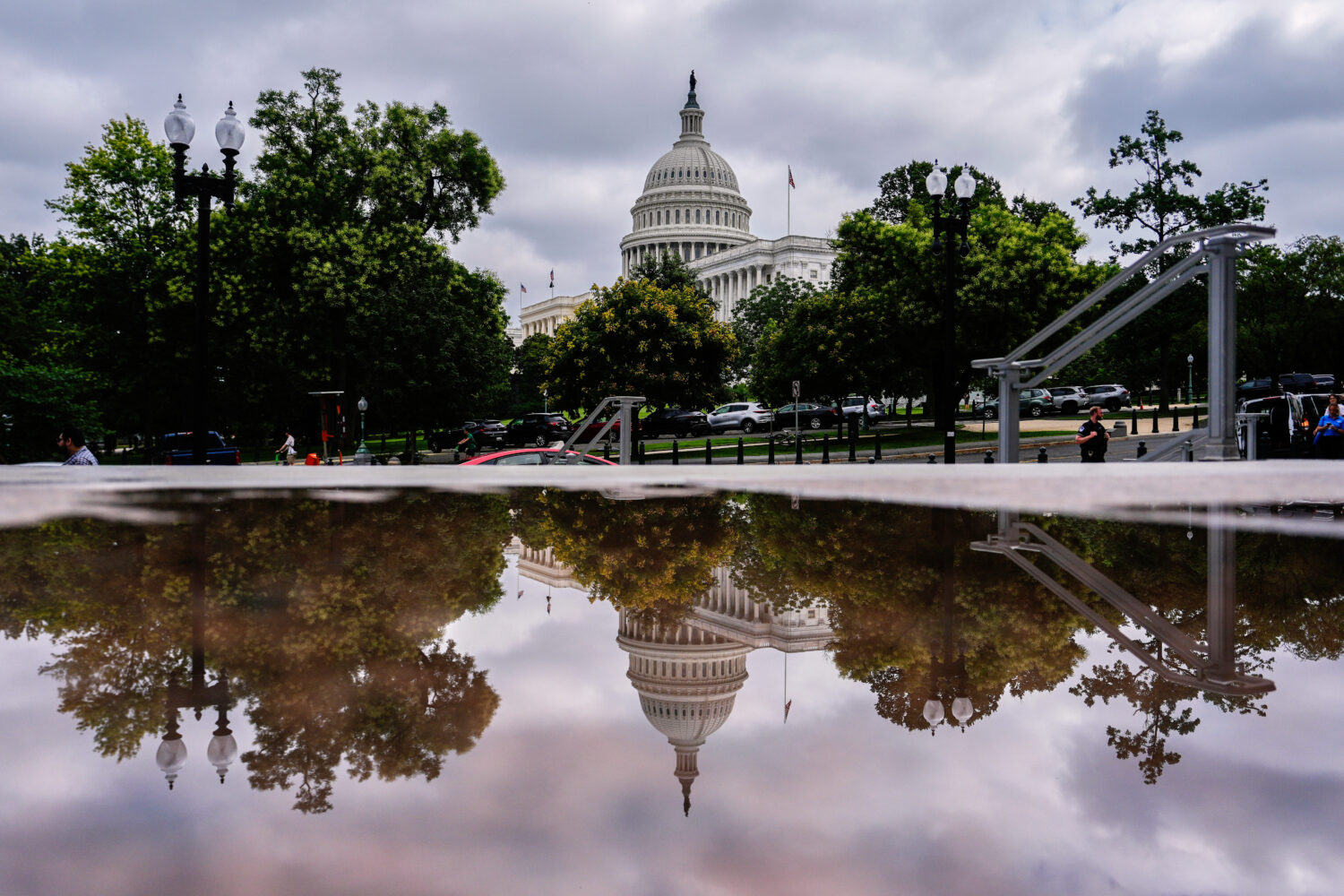 The U.S. Capitol is reflected in a puddle outside of the Rayburn House Office Building, Wednesday, ...