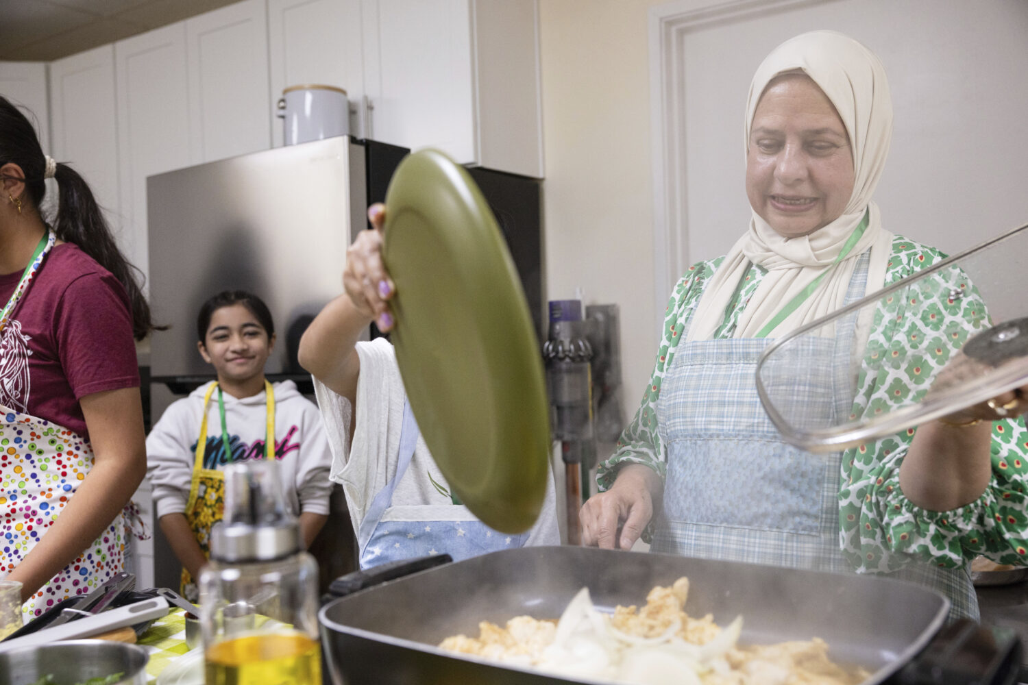 Shameem Syed, right, teaches students how to make a chicken stir fry during a cooking class at Oliv...