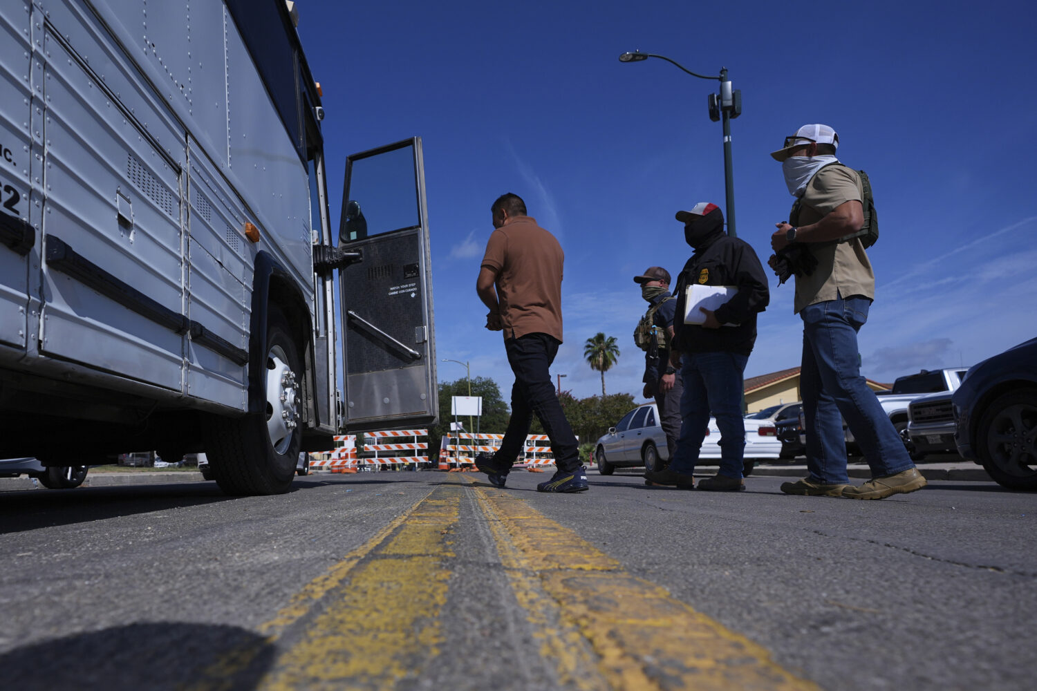 Federal agents escort a man to a transport bus after he was detained following an appearance at imm...