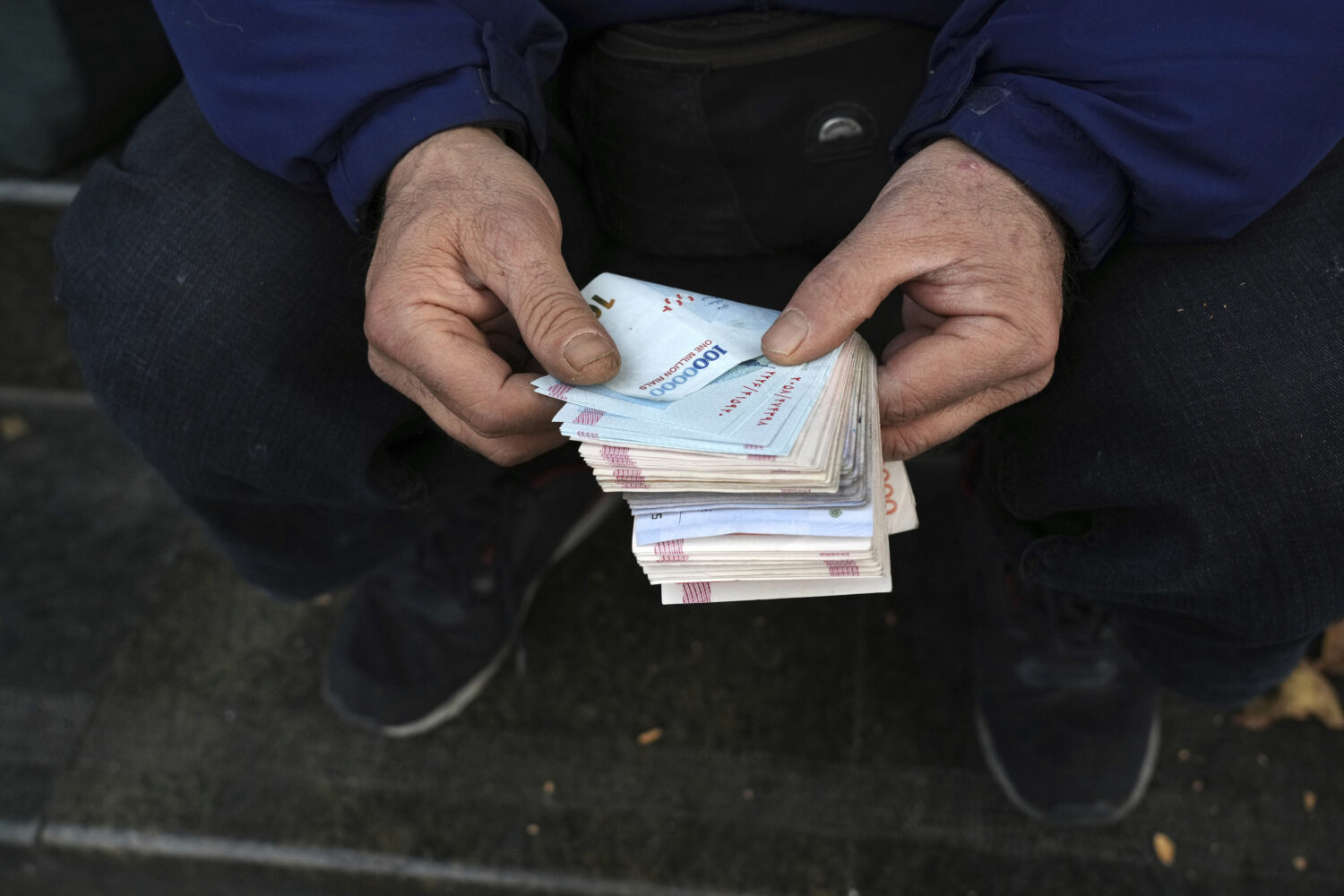FILE - A street money exchanger poses for a photo without showing his face as he counts Iranian ban...