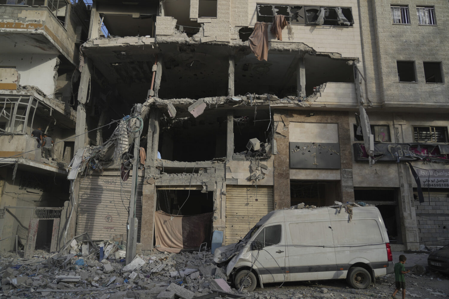A Palestinian boy walks past a heavily damaged building in the Rimal neighborhood, in Gaza City, Su...