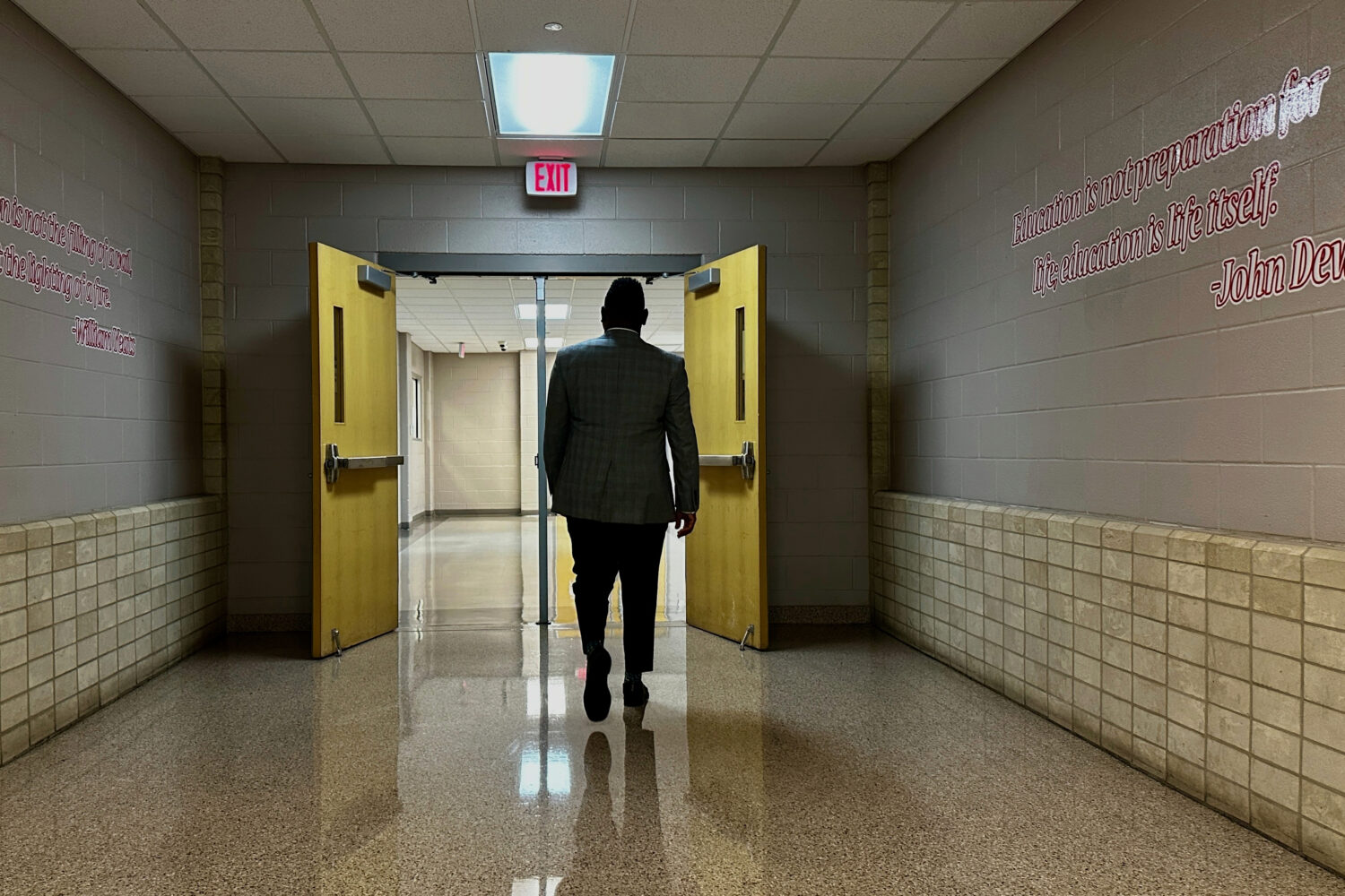 Chief of Talent at New Schools for New Orleans, Jahquille Ross, walks down a hallway at Alice Hart ...