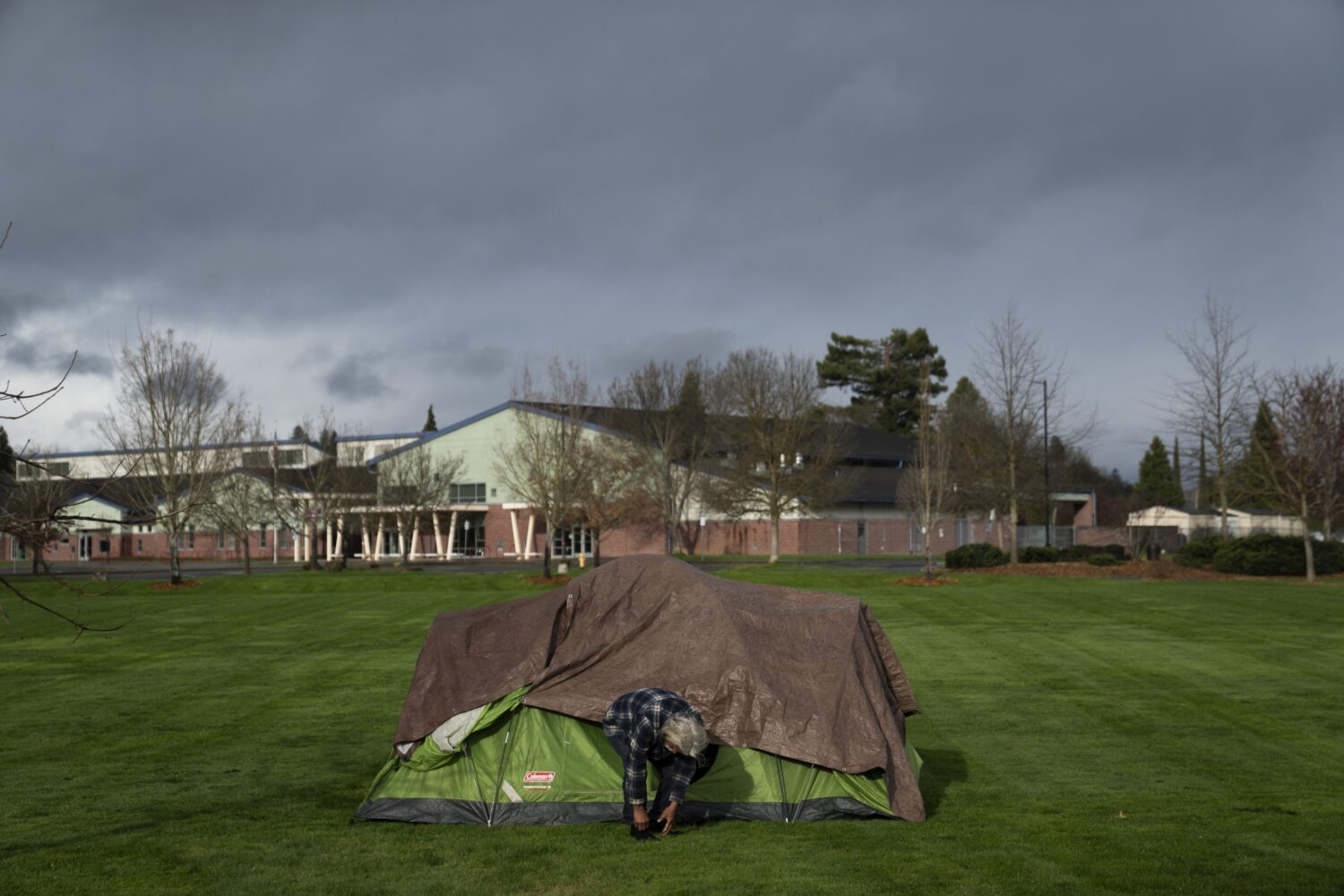 FILE - With Fruitdale Elementary School in the background, a homeless man adjusts his shoe at Fruit...