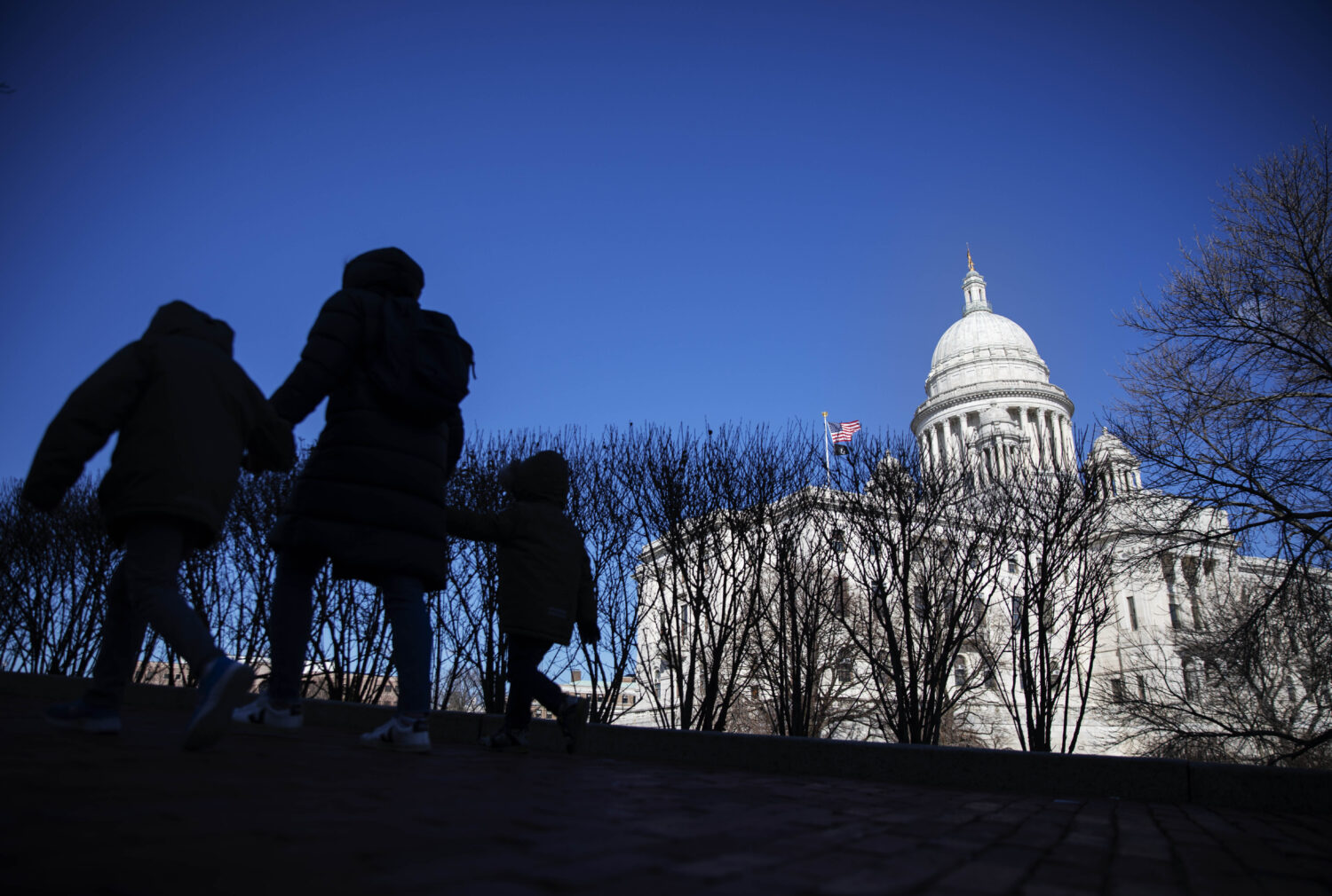 FILE - Pedestrians walk past the Rhode Island Statehouse, March 1, 2020, in Providence, R.I. (AP Ph...