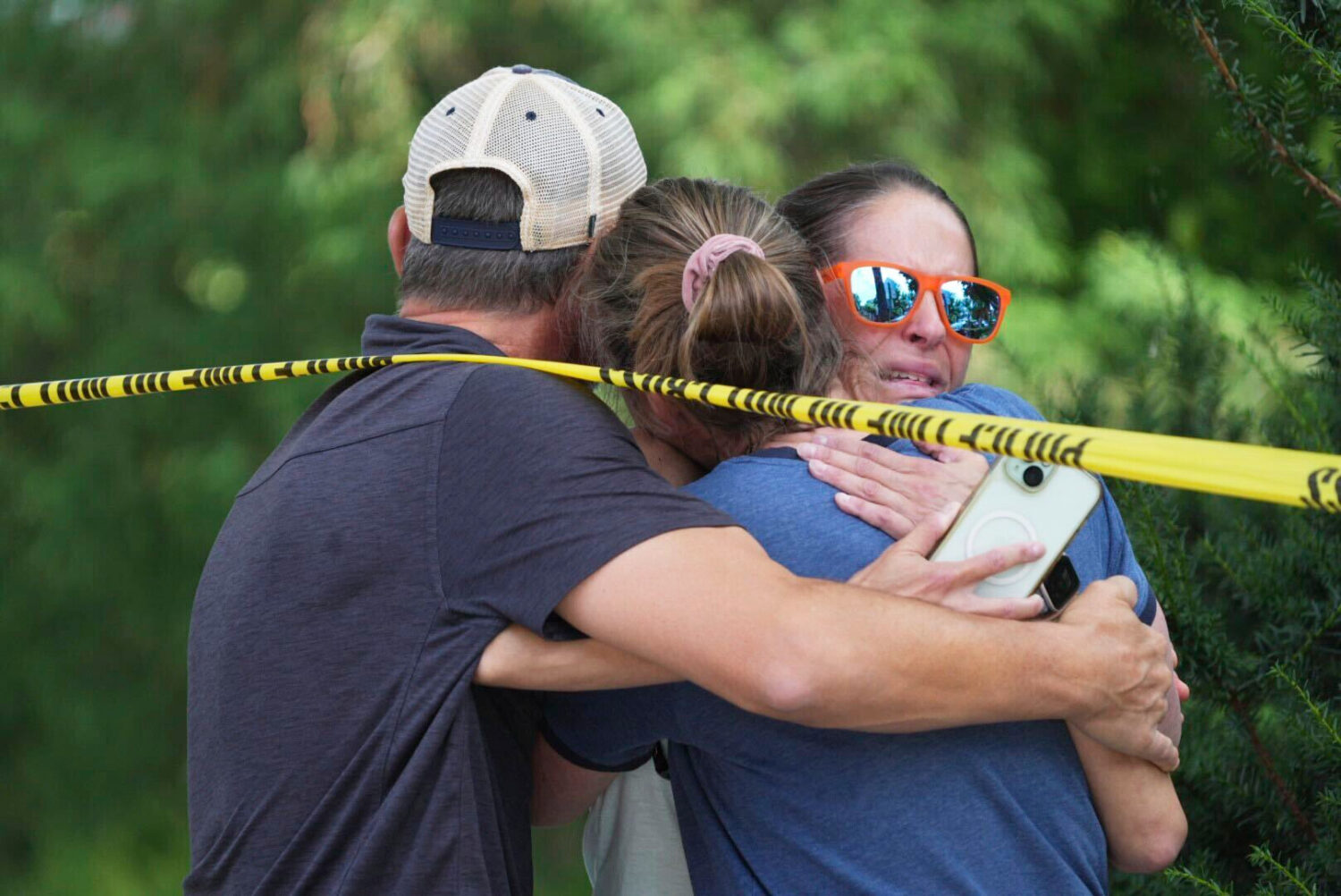 Community members embrace after a shooting at the Annunciation Catholic School on Wednesday, Aug. 2...