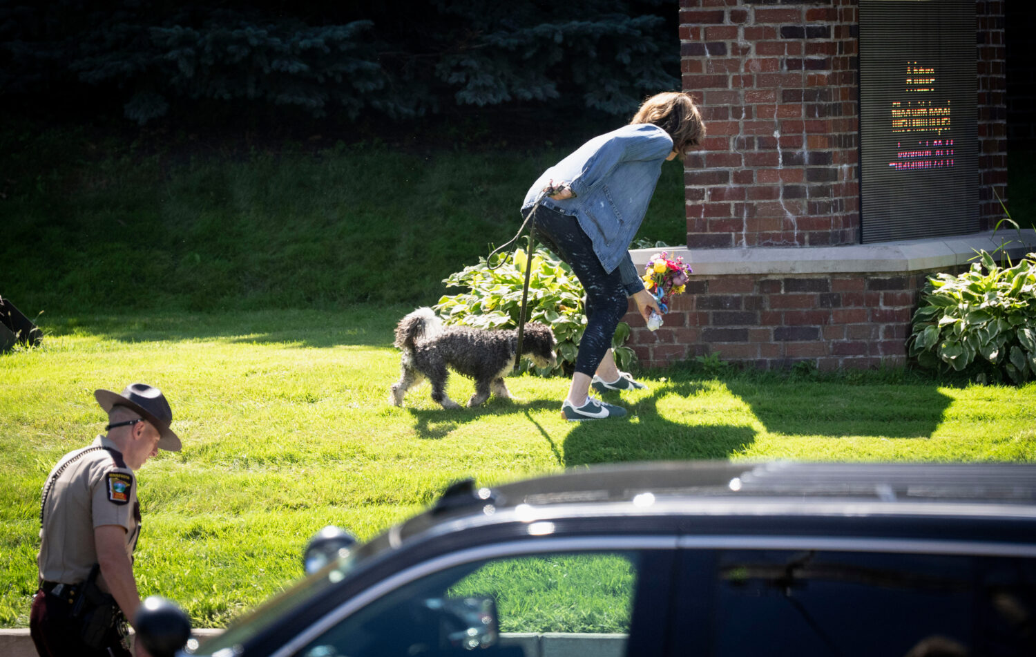 A woman is allowed to drop off flowers at the Annunciation Catholic School sign near the scene of a...