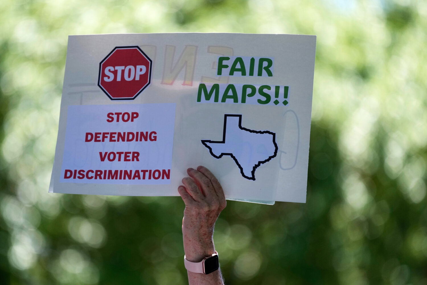 A woman holds a sign during a rally to protest against redistricting hearings at the Texas Capitol,...