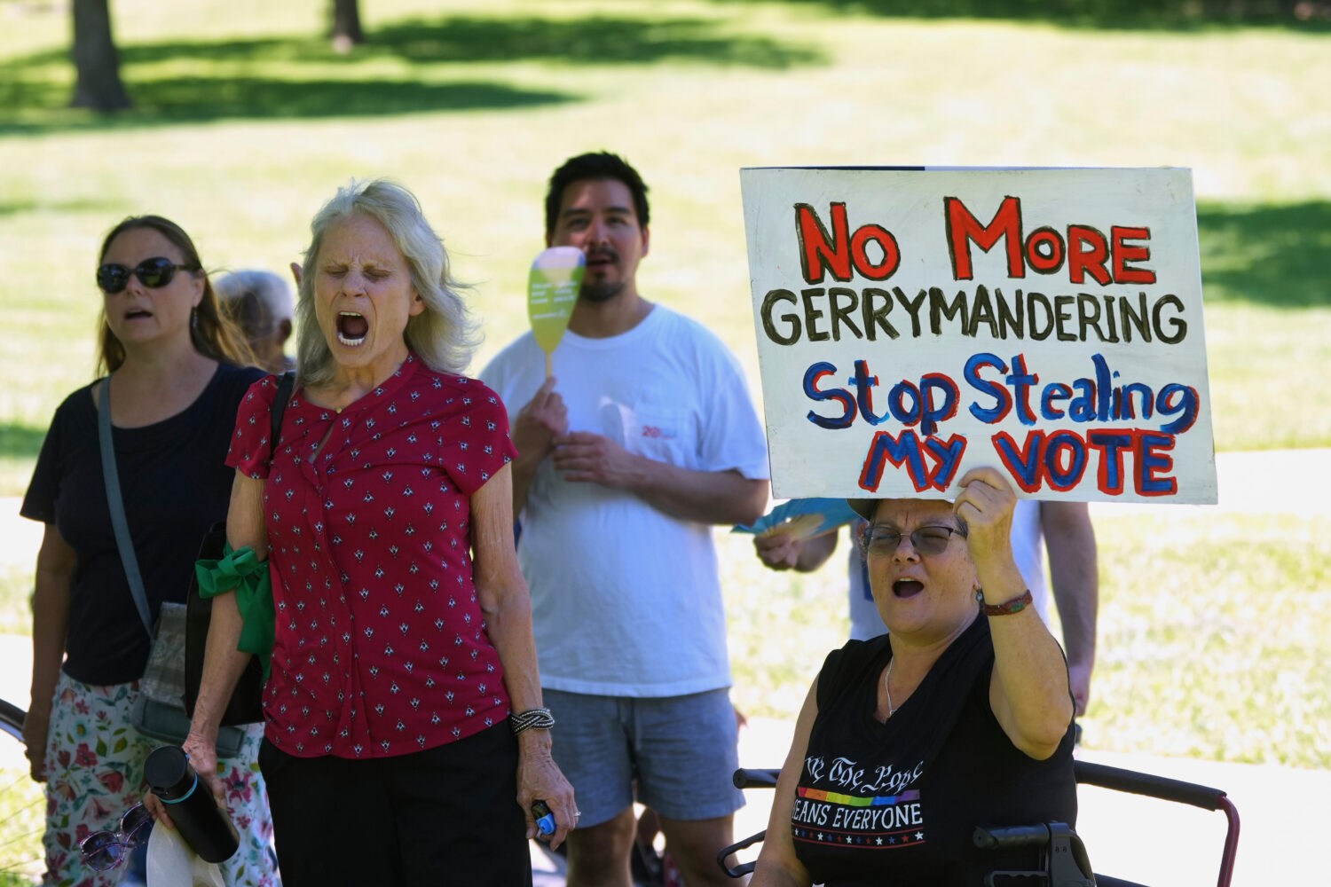 A woman holds a sign as she joins others during a rally to protest against redistricting hearings a...