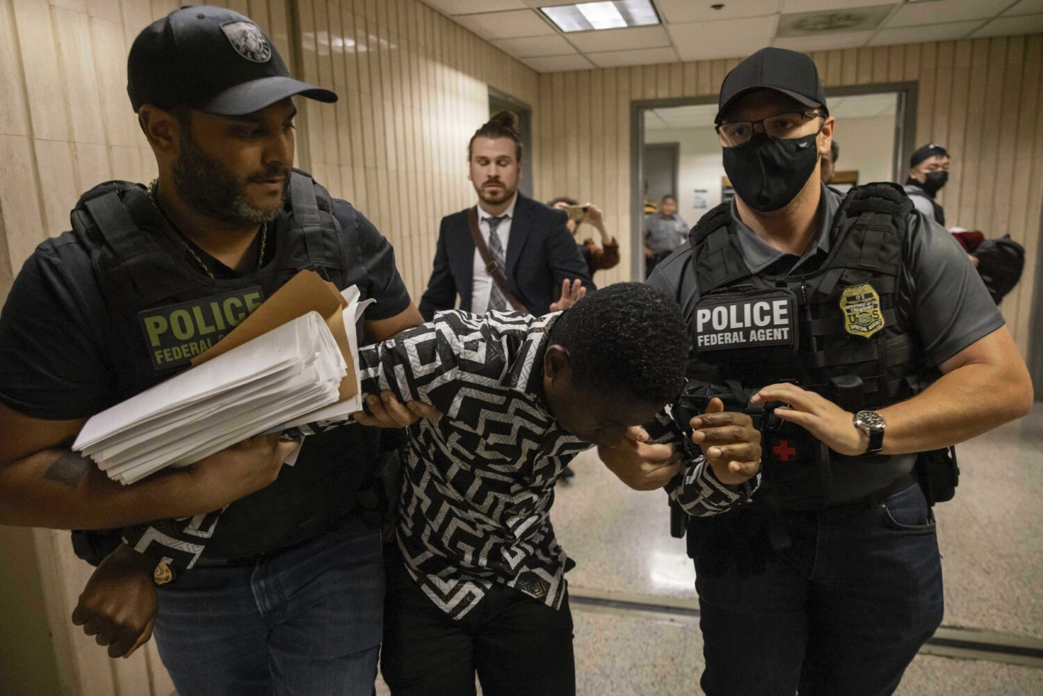 FILE - Federal agents including Immigration and Customs Enforcement detain a person outside an immi...
