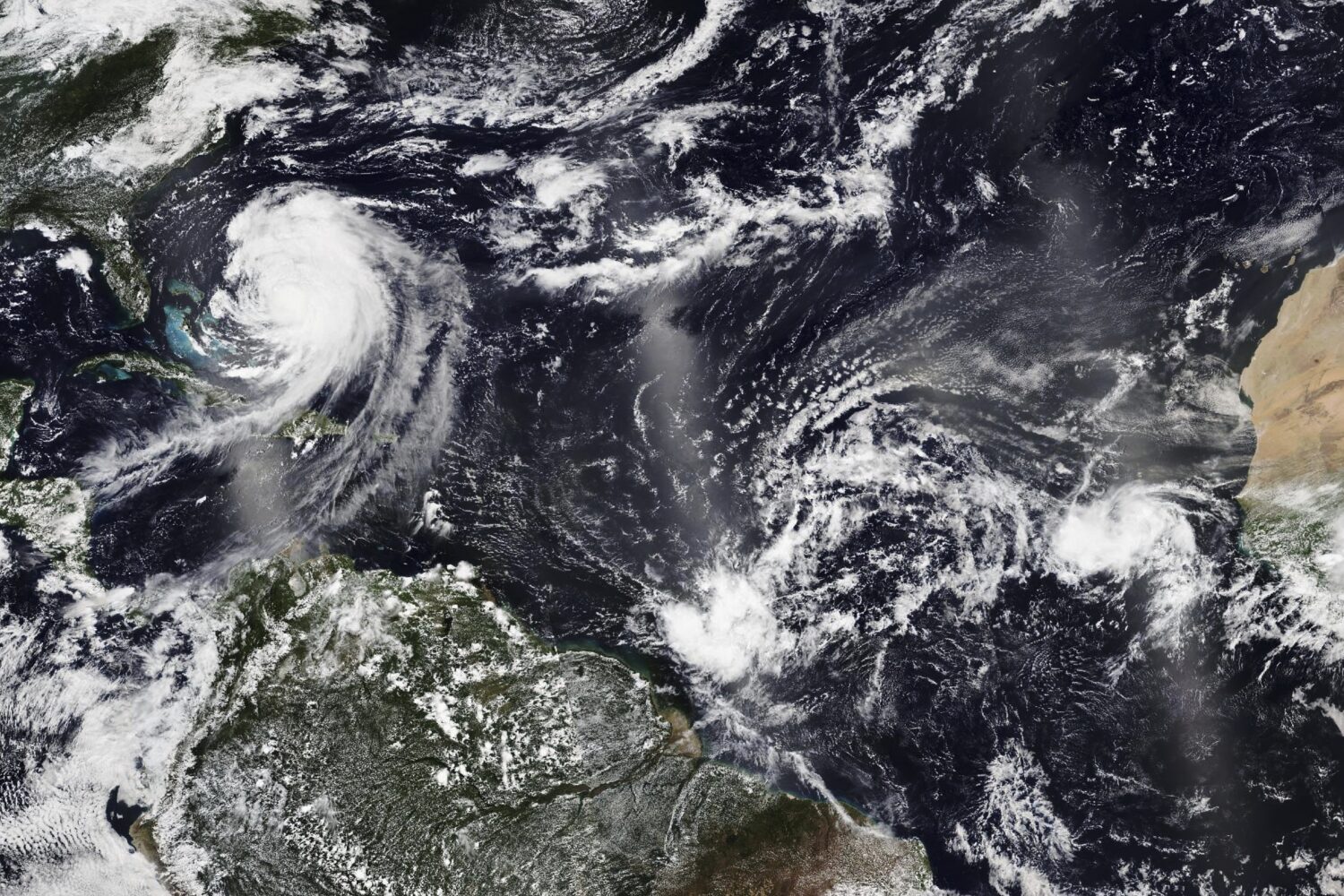 In this Tuesday, Aug. 19, 2025, satellite image released by NASA, Hurricane Erin, left, continues i...