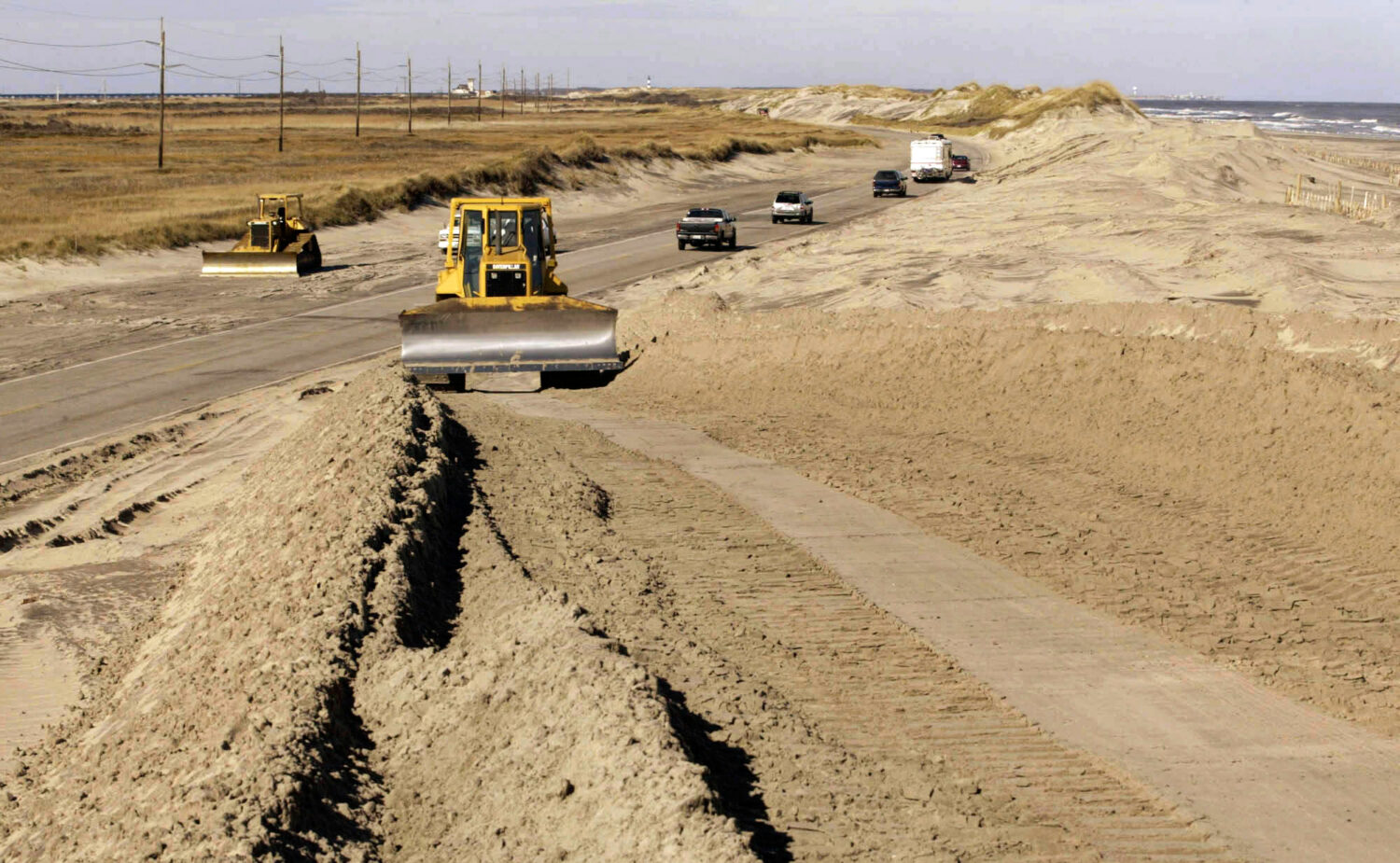 FILE - A bulldozer pushes sand along NC highway 12 in the Pea island National Wildlife Refuge, on N...