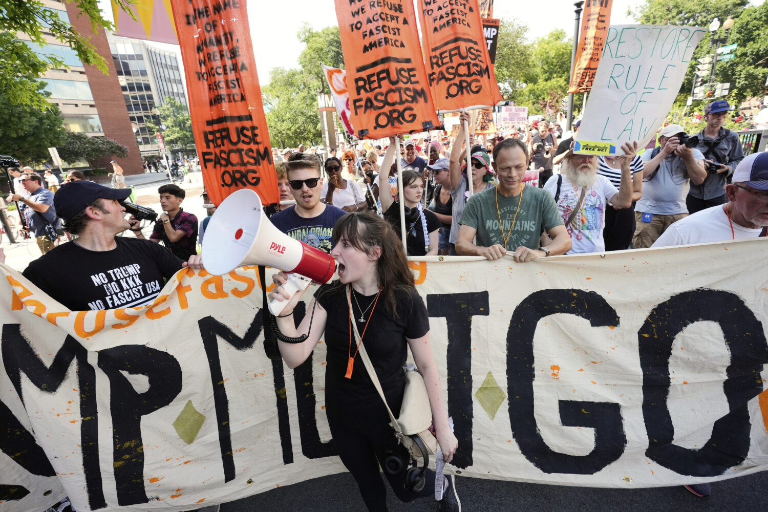 Activists carrying signs march to the White House to protest President Donald Trump's federal takeo...