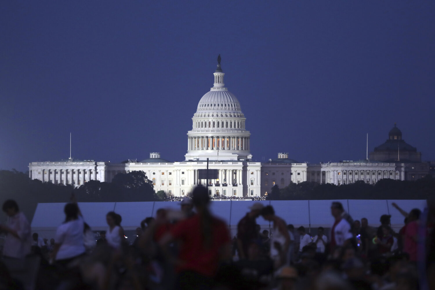 The U.S. Capitol building stands as people wait to watch fireworks near the Washington Monument dur...