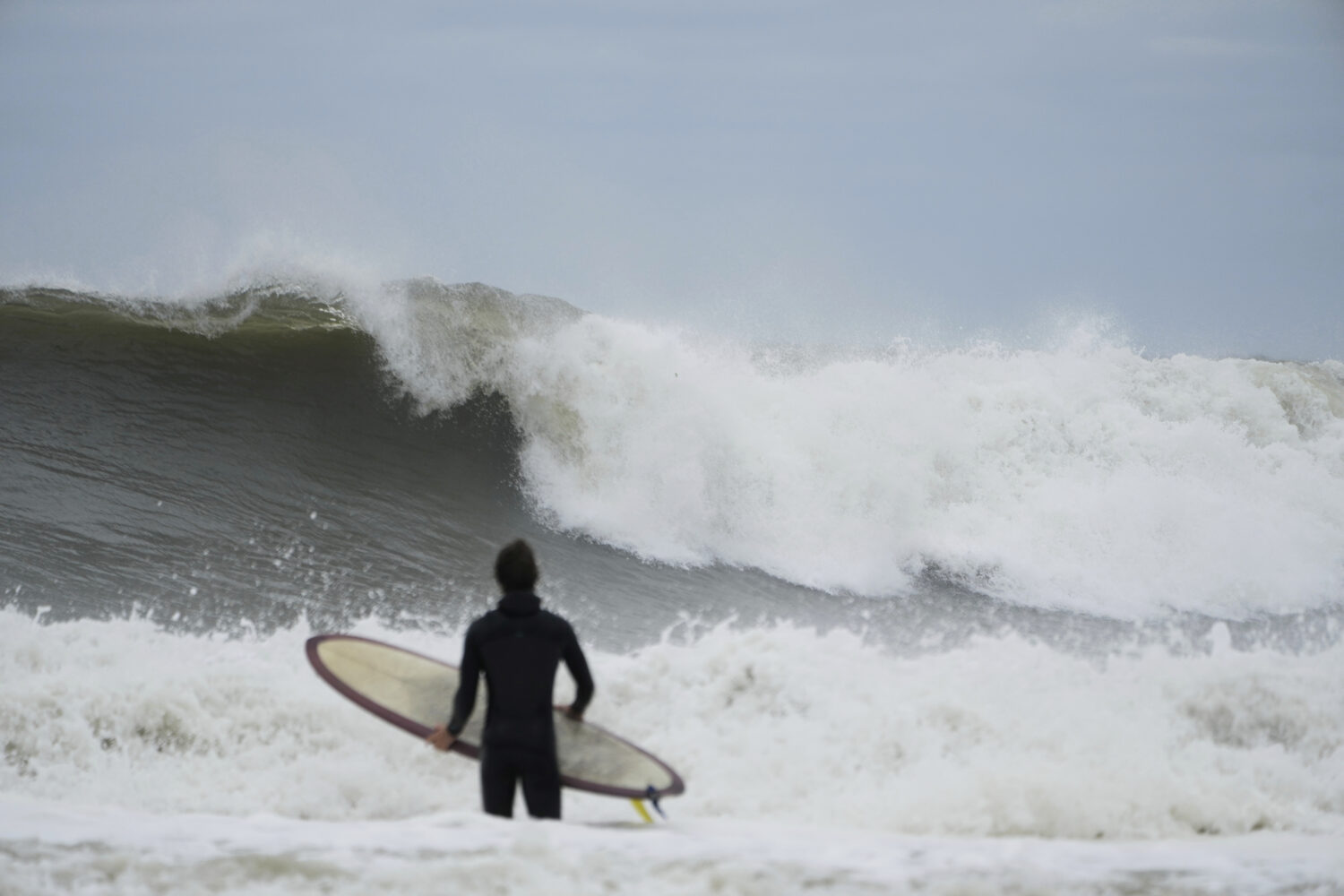 A surfer tries to get in the water, past big waves bolstered by Hurricane Erin, at Rockaway Beach i...