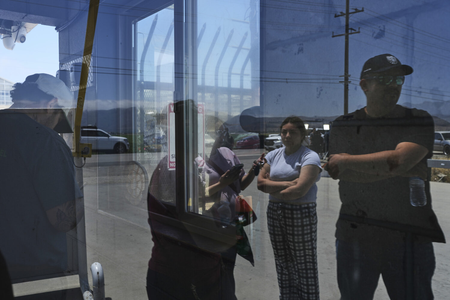 FILE - People wait outside of Glass House Farms, a day after an immigration raid on the facility, F...