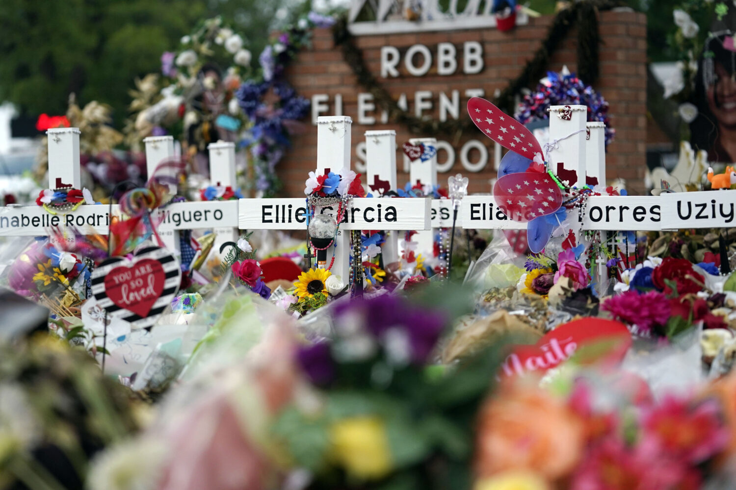 FILE - Crosses are surrounded by flowers and other mementos at a memorial, June 9, 2022, for the vi...