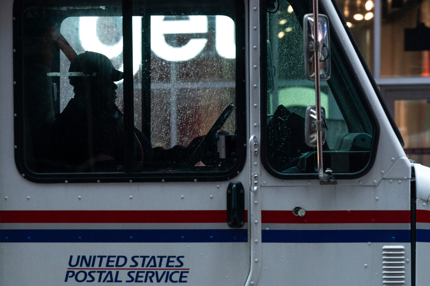 FILE - A United States Postal Service driver sits behind the wheel of a mail truck in Times Square,...