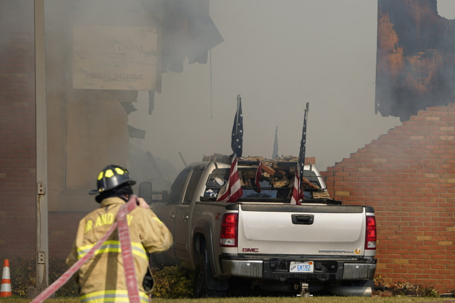 A vehicle that was rammed into the building is surrounded by smoke as a firefighter works on the sc...
