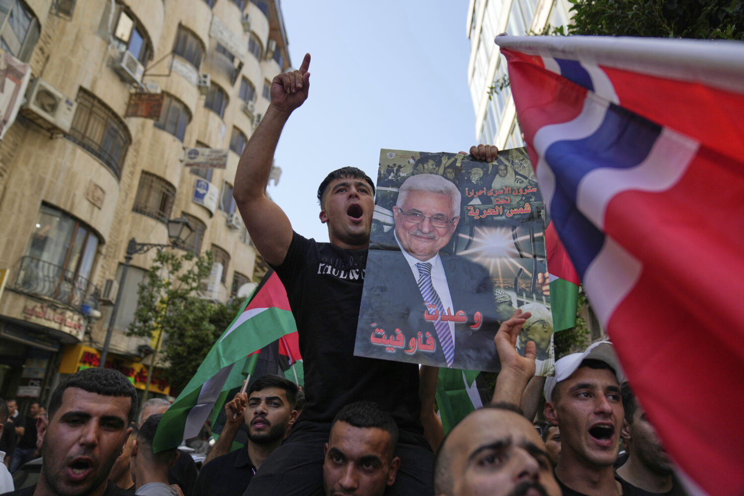 Palestinians chant national slogans and carry posters with pictures of President Mahmoud Abbas and ...