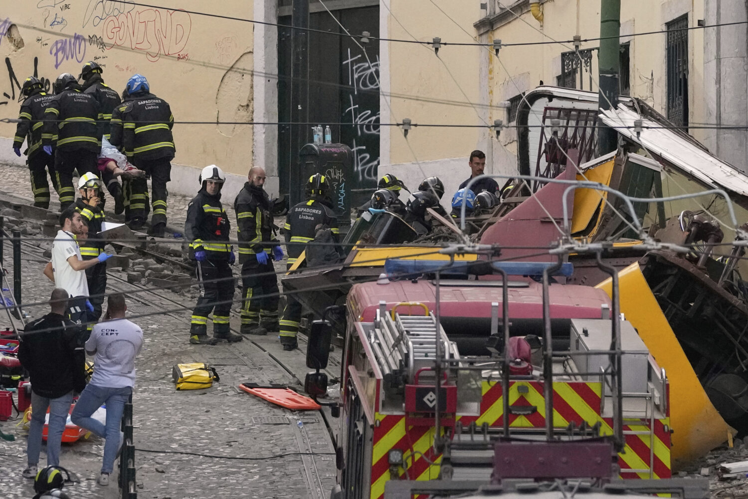 Firefighters carrying the body of a person on a stretcher at the site of a derailed electric street...