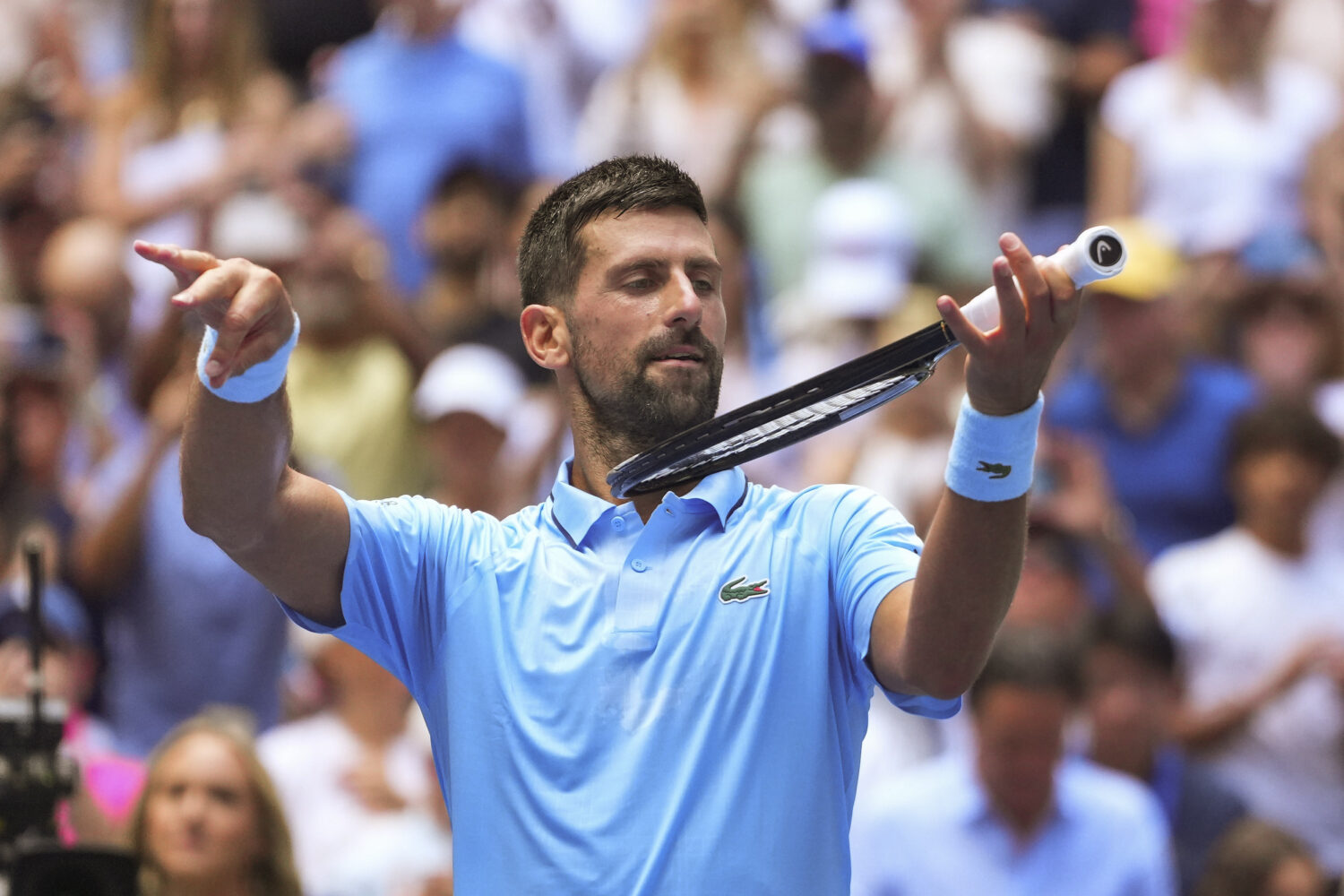 Novak Djokovic, of Serbia, pretends to play the violin after defeating Zachary Svajda, of the Unite...