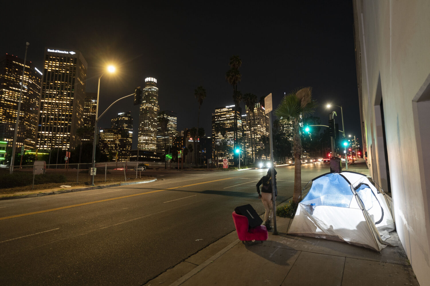 FILE - In this photo illuminated by an off-camera flash, a woman walks past a homeless person's ten...