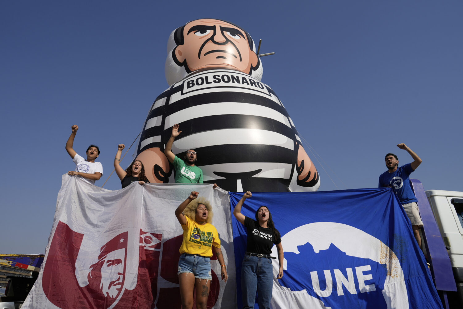 University students display an inflatable doll of Brazil's former President Jair Bolsonaro wearing ...