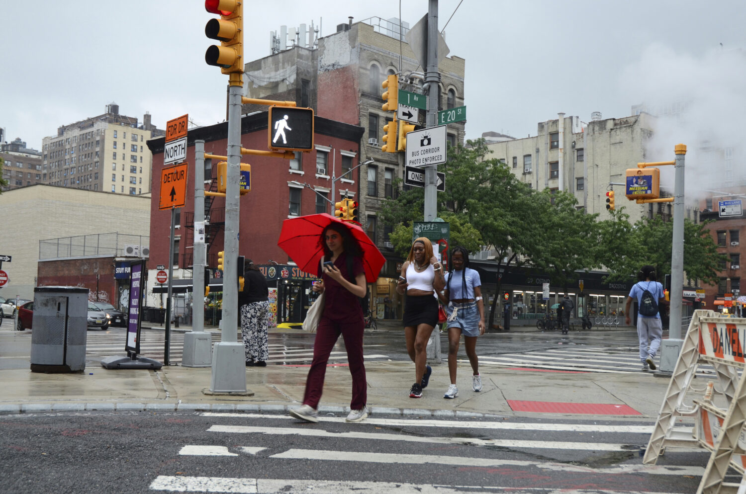 FILE - Pedestrians walk in the rain on 20th Street and First Avenue, Thursday, July 31, 2025, in Ne...