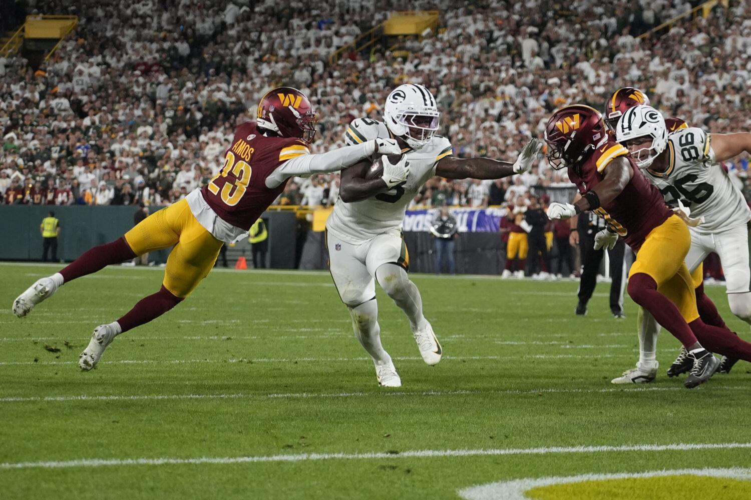 Green Bay Packers running back Josh Jacobs runs with the ball as Washington Commanders cornerback T...