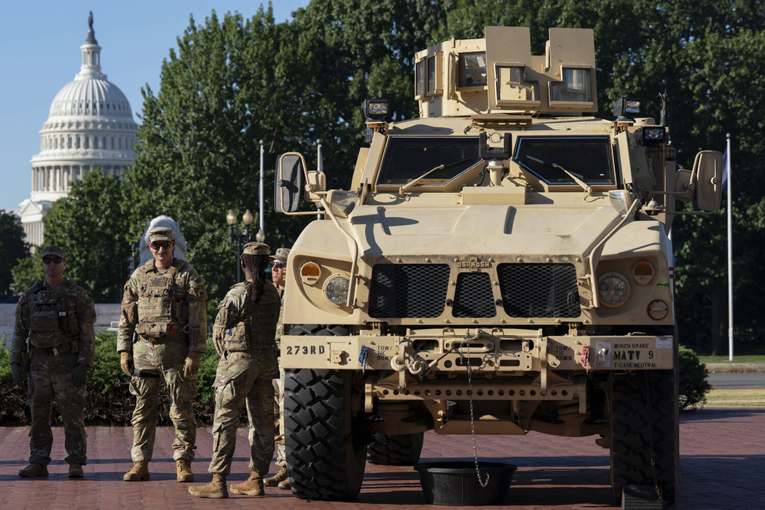 Members of the District of Columbia National Guard standing next to an MATV vehicle scan the area a...