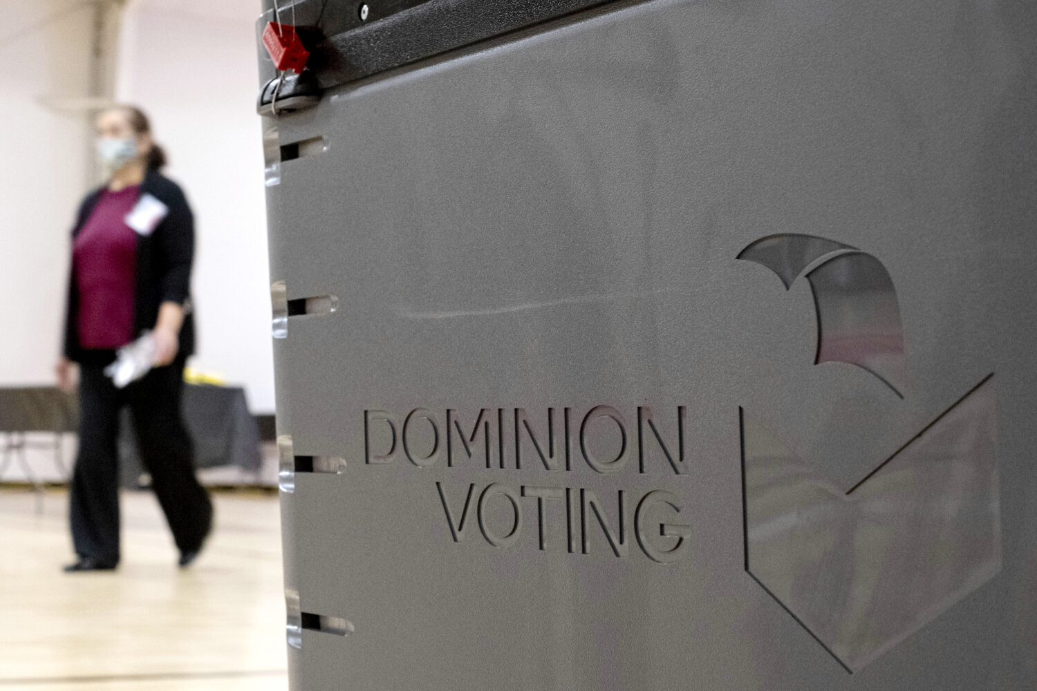 FILE - A worker passes a Dominion Voting ballot scanner while setting up a polling location at an e...
