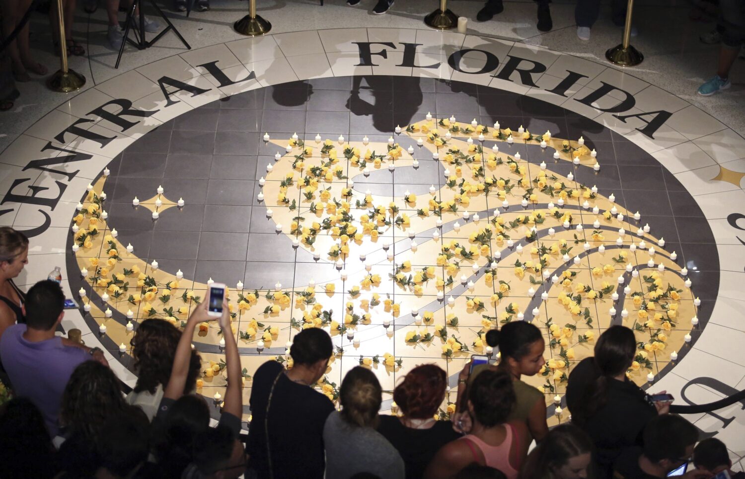 FILE - Students gather around lit candles surrounding the UCF logo, June 14, 2016. (Stephen M. Dowe...