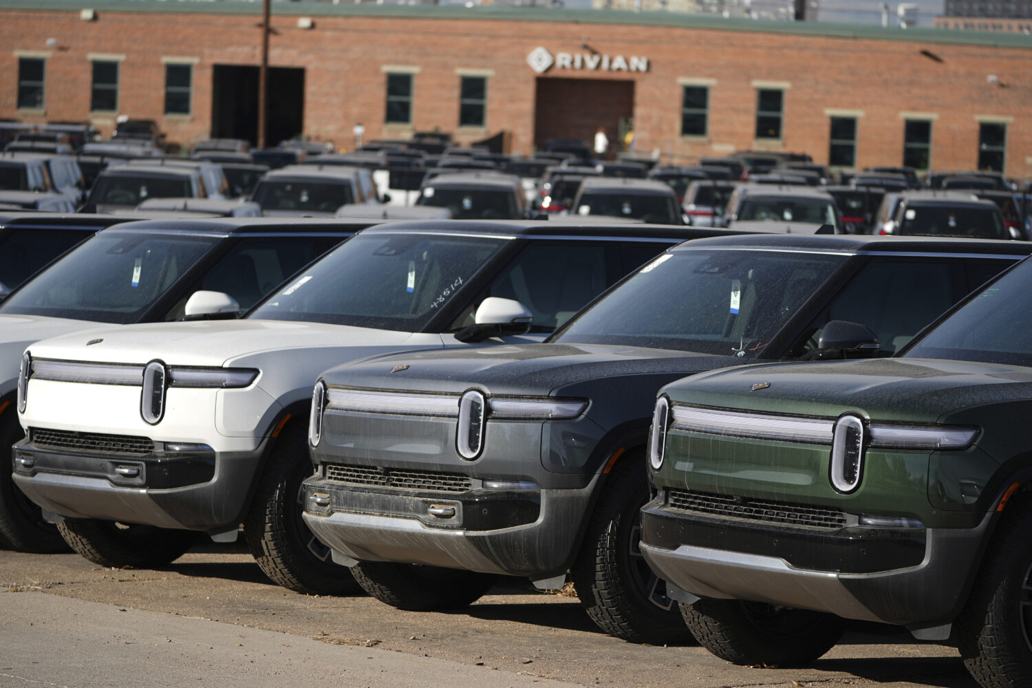 FILE - A long line of unsold 2024 R1S electric utility vehicles sits at a Rivian service center Nov...