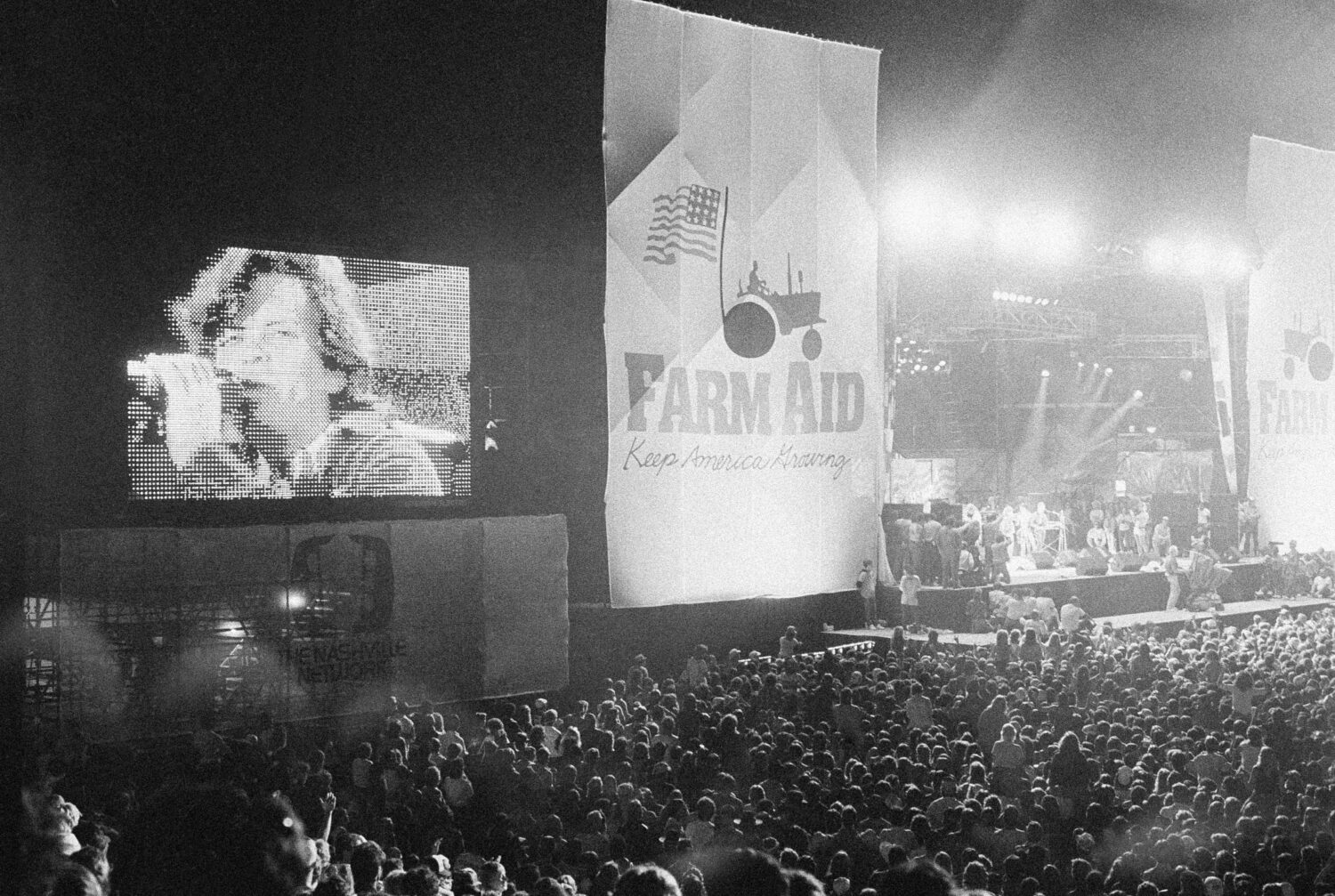 FILE - John Cougar Mellencamp performs both on stage and on one of two large screen television scre...