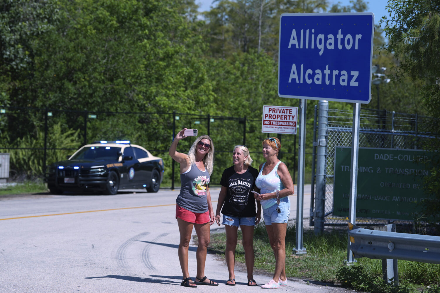 A group of women pose for a selfie in front of the "Alligator Alcatraz" sign at the entrance to an ...