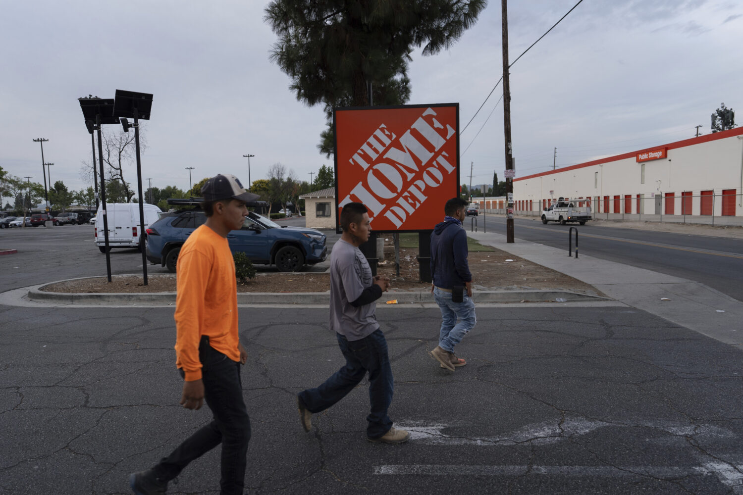 Workers walk toward a food vendor past a Home Depot sign in the Van Nuys section of Los Angeles, Au...