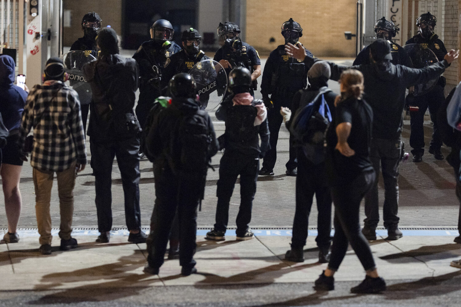 Protesters yell at officers as they walk back to the gates after they created a path for vehicles t...