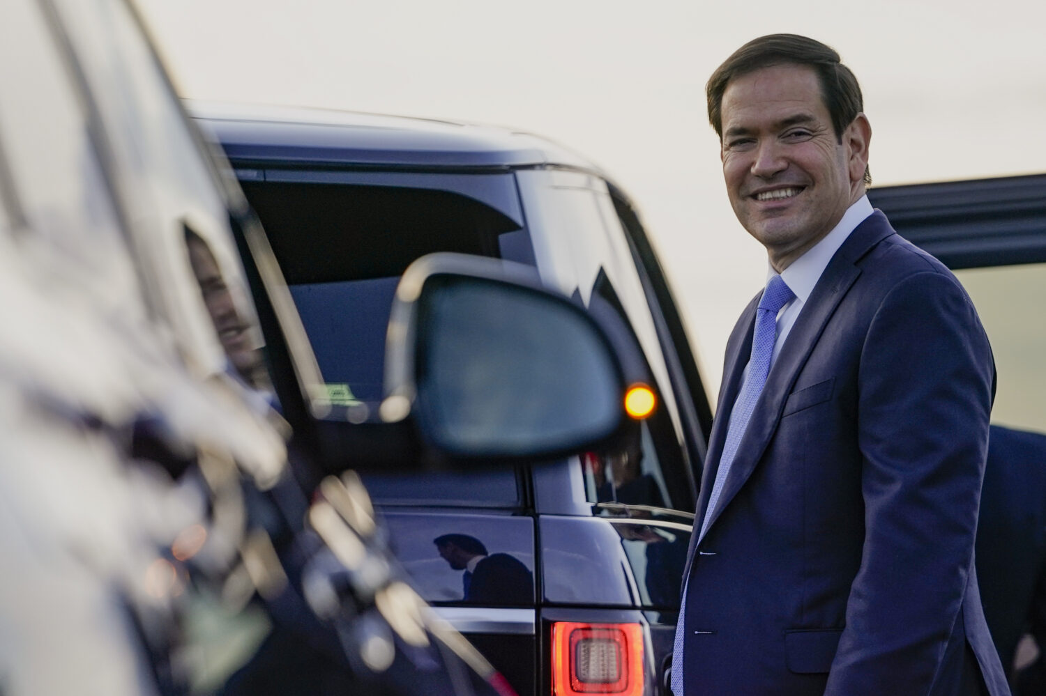 U.S. Secretary of State Marco Rubio smiles as he prepares to enter a vehicle upon arrival at London...