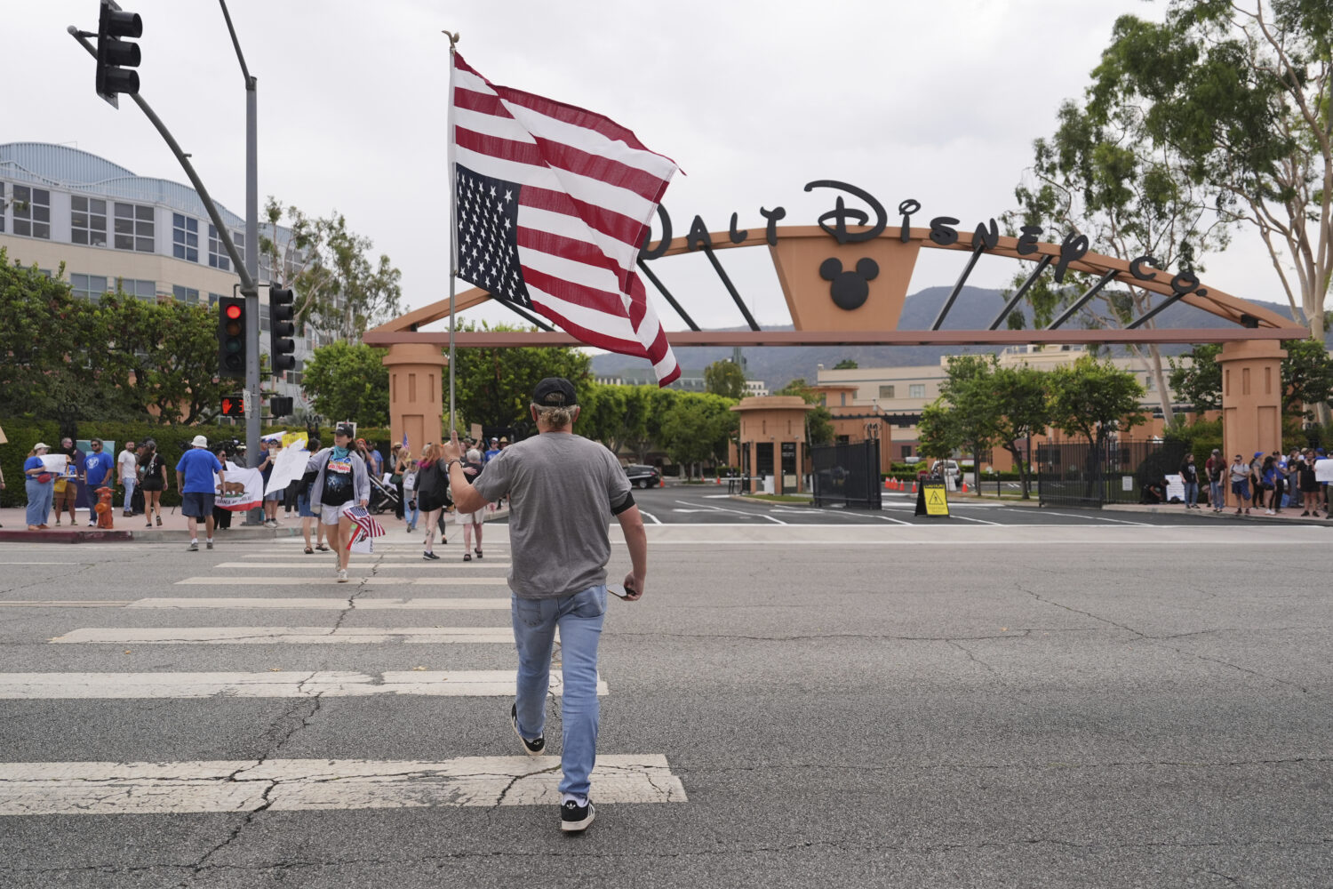 A U.S. flag is carried across a street in front of a demonstration in response to the suspension of...