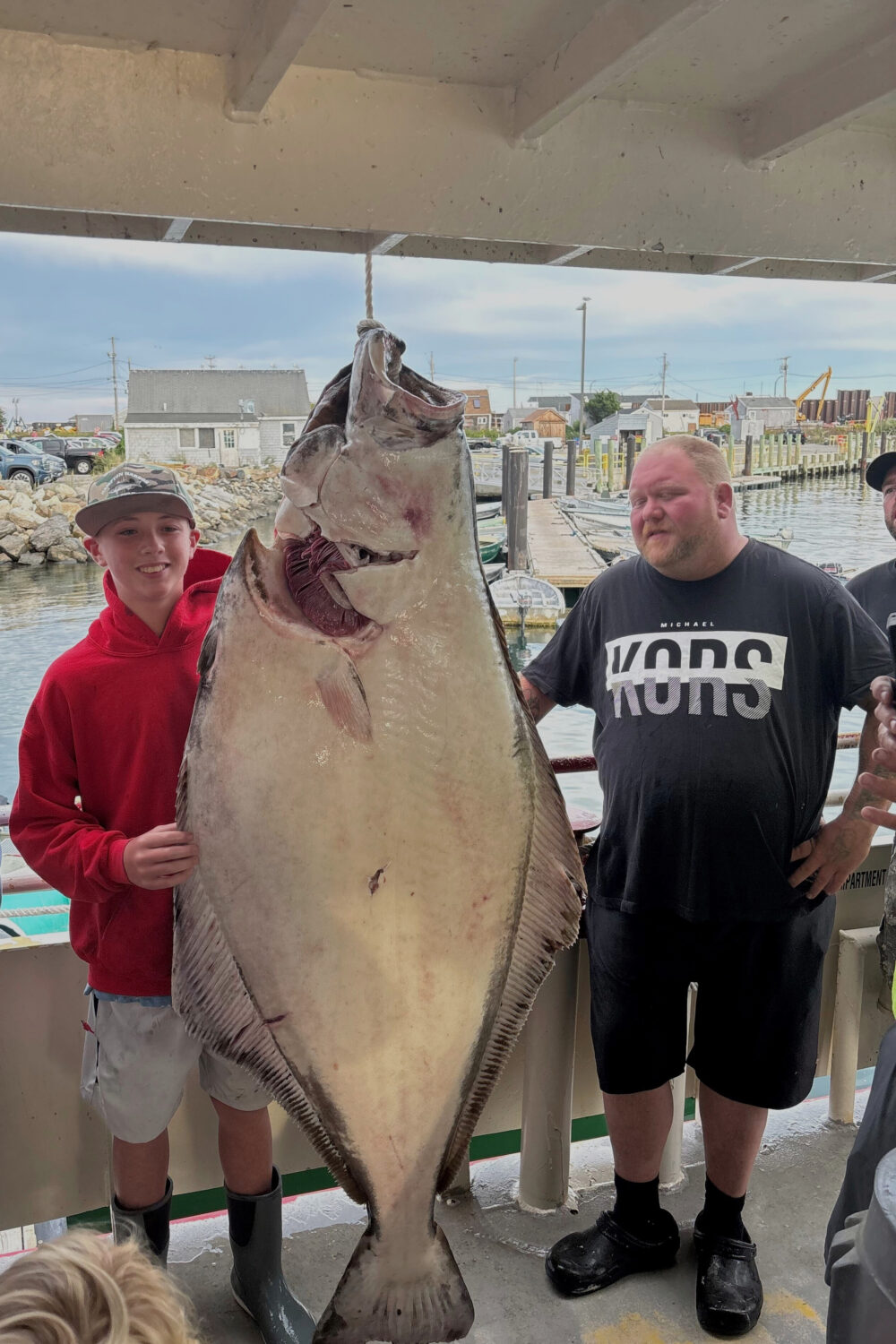 This photo provided by Jill Denio, Jackson Denio stands with a 177-pound halibut he caught Monday o...
