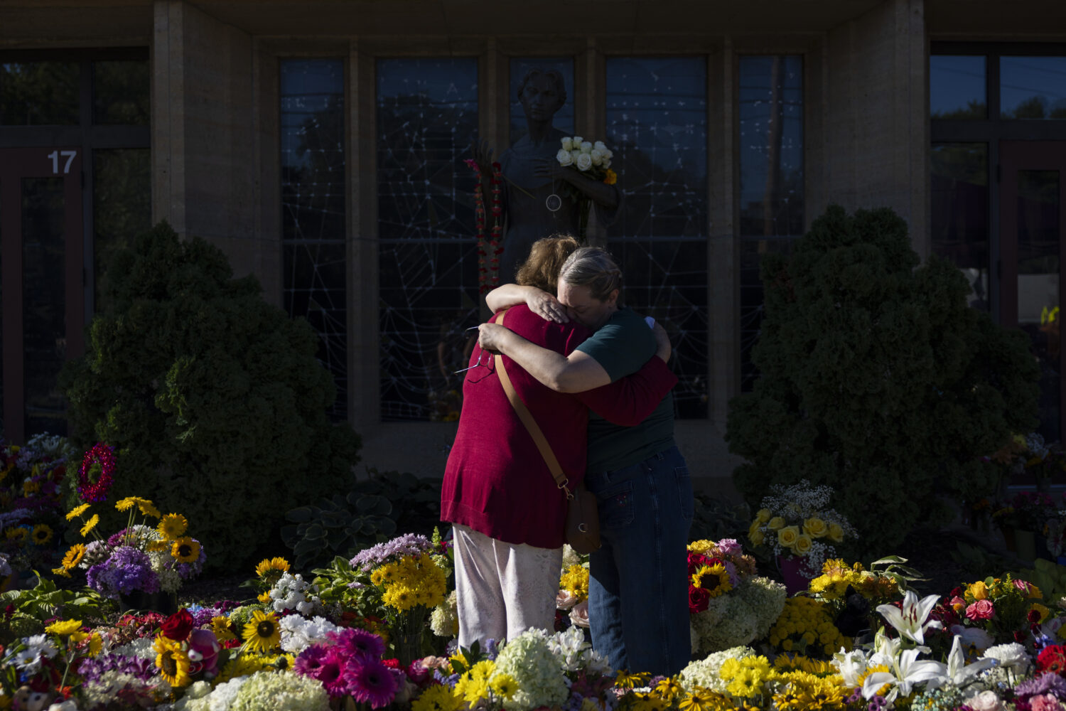 Women embrace at the memorial outside the Annunciation Catholic Church following Wednesday's shooti...