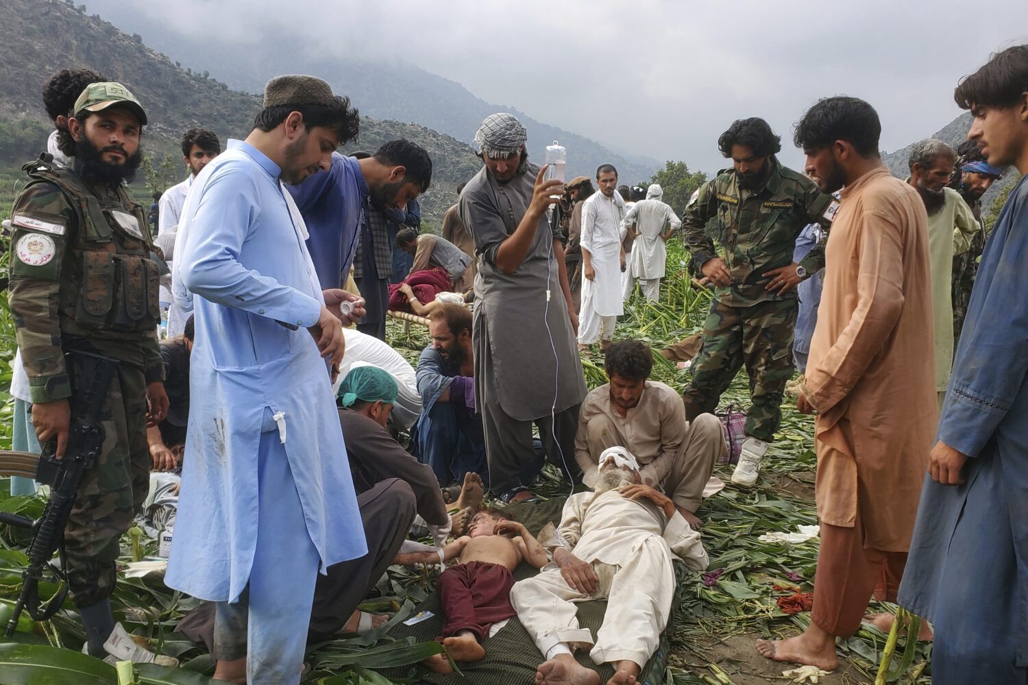 Civil defense workers, locals, and army soldiers prepare to evacuate injured victims of an earthqua...