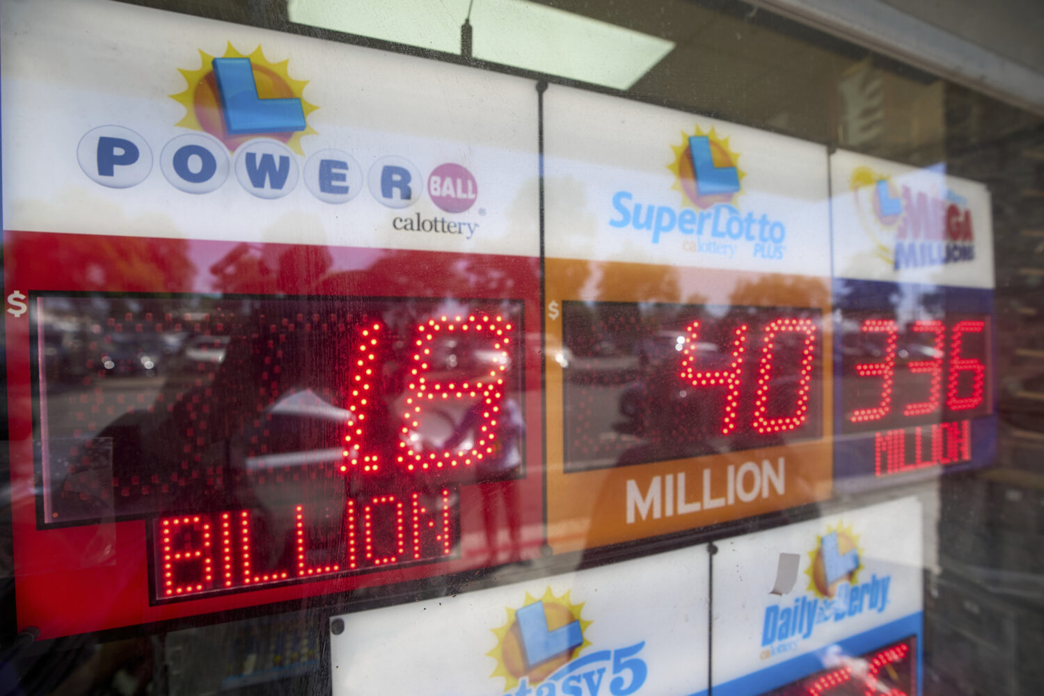 An electronic sign reads $1.8 billion as crowds wait in line to buy lottery tickets at the Bluebird...