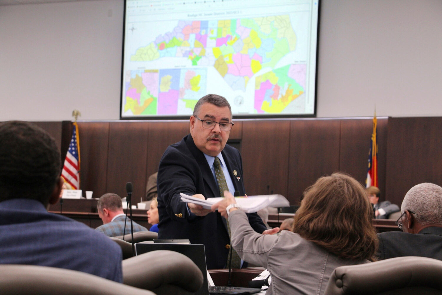 FILE - A sergeant-at-arms in the North Carolina state Senate passes out copies of a map proposal fo...