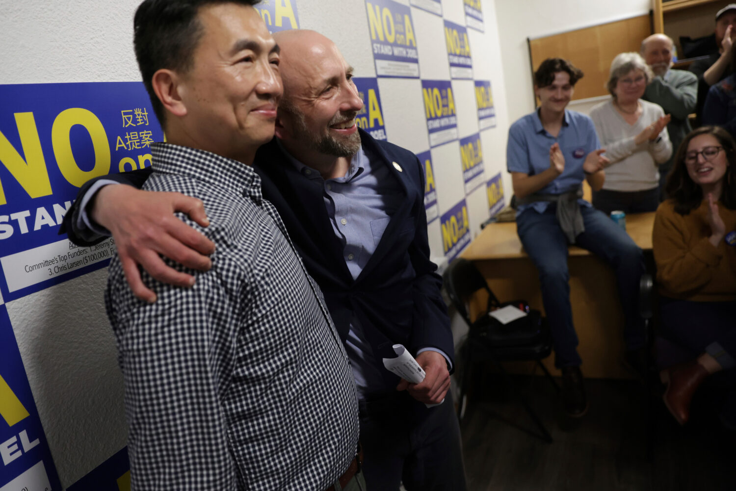 Supervisor Joel Engardio, second left, hugs his husband, Lionel Hsu, as supporters applaud after En...