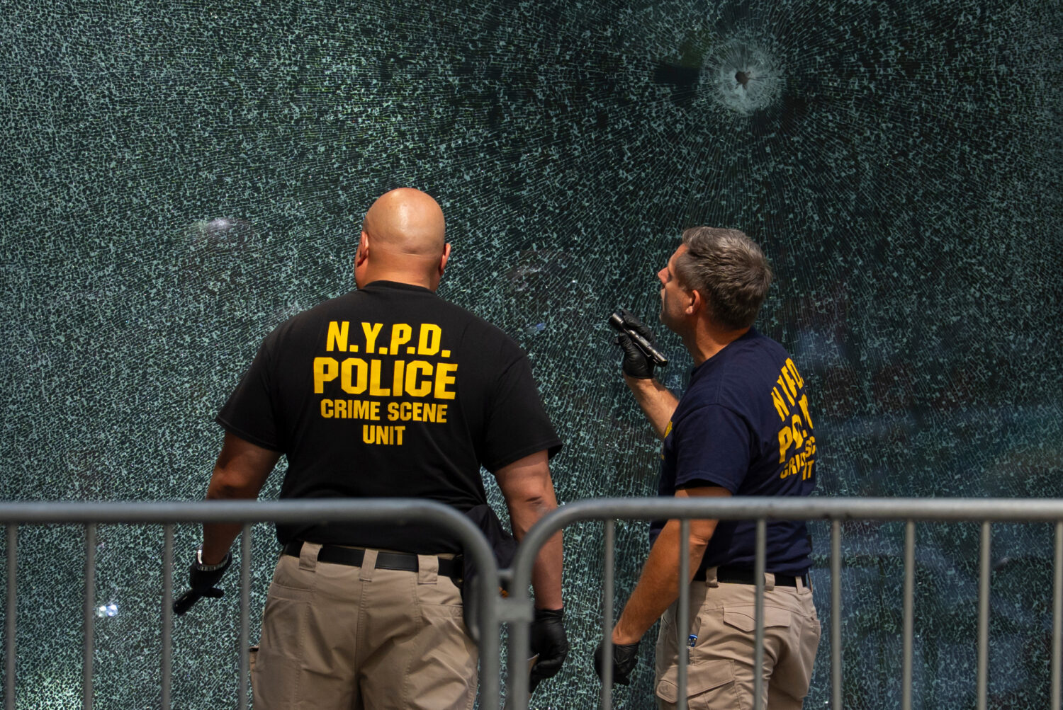 FILE - Members of the NYPD's Crime Scene Unit examine a door with bullet holes, Tuesday, July 29, 2...