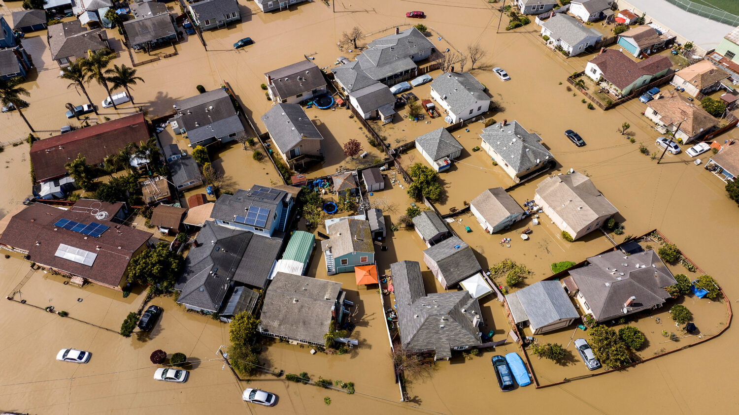 FILE - Floodwaters surround homes and vehicles in the community of Pajaro in Monterey County, Calif...