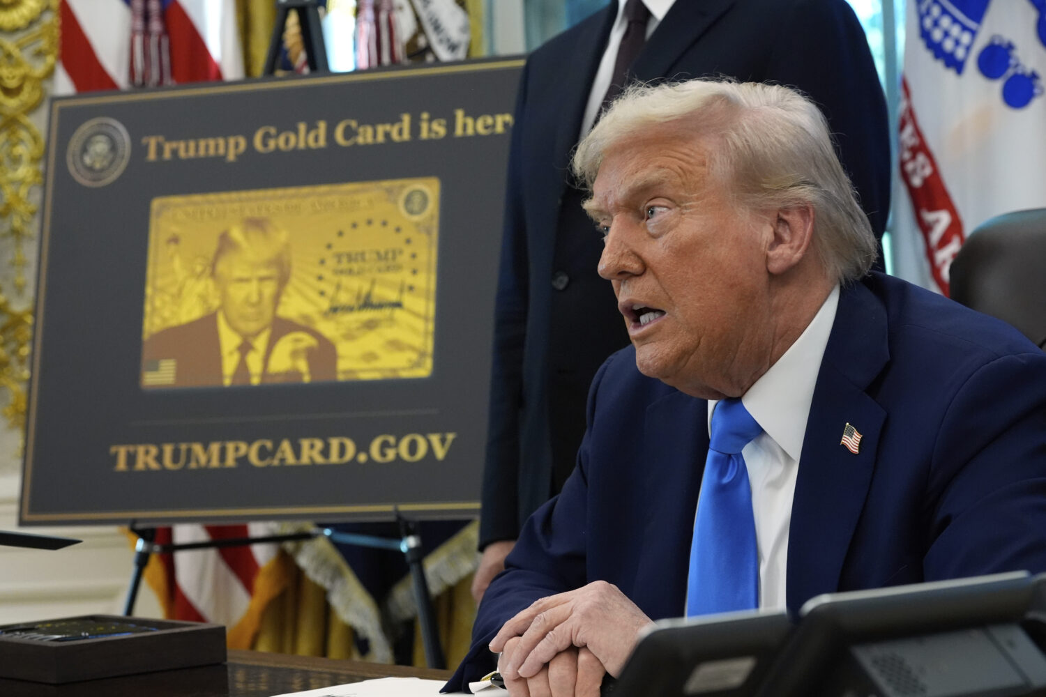 A poster showing the Trump Gold Card is seen as President Donald Trump signs executive orders in th...