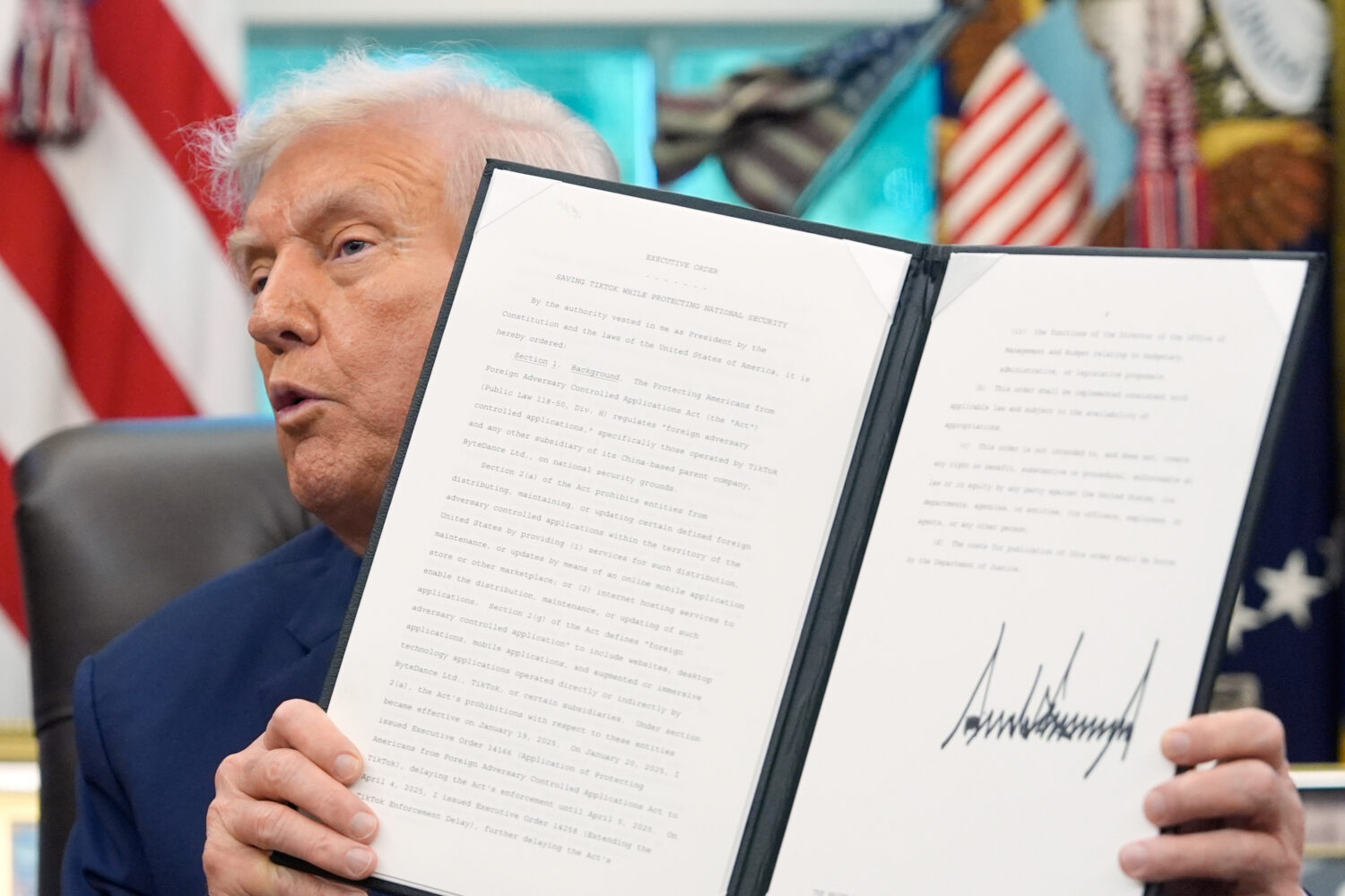President Donald Trump holds a signed executive order regarding TikTok in the Oval Office at the Wh...