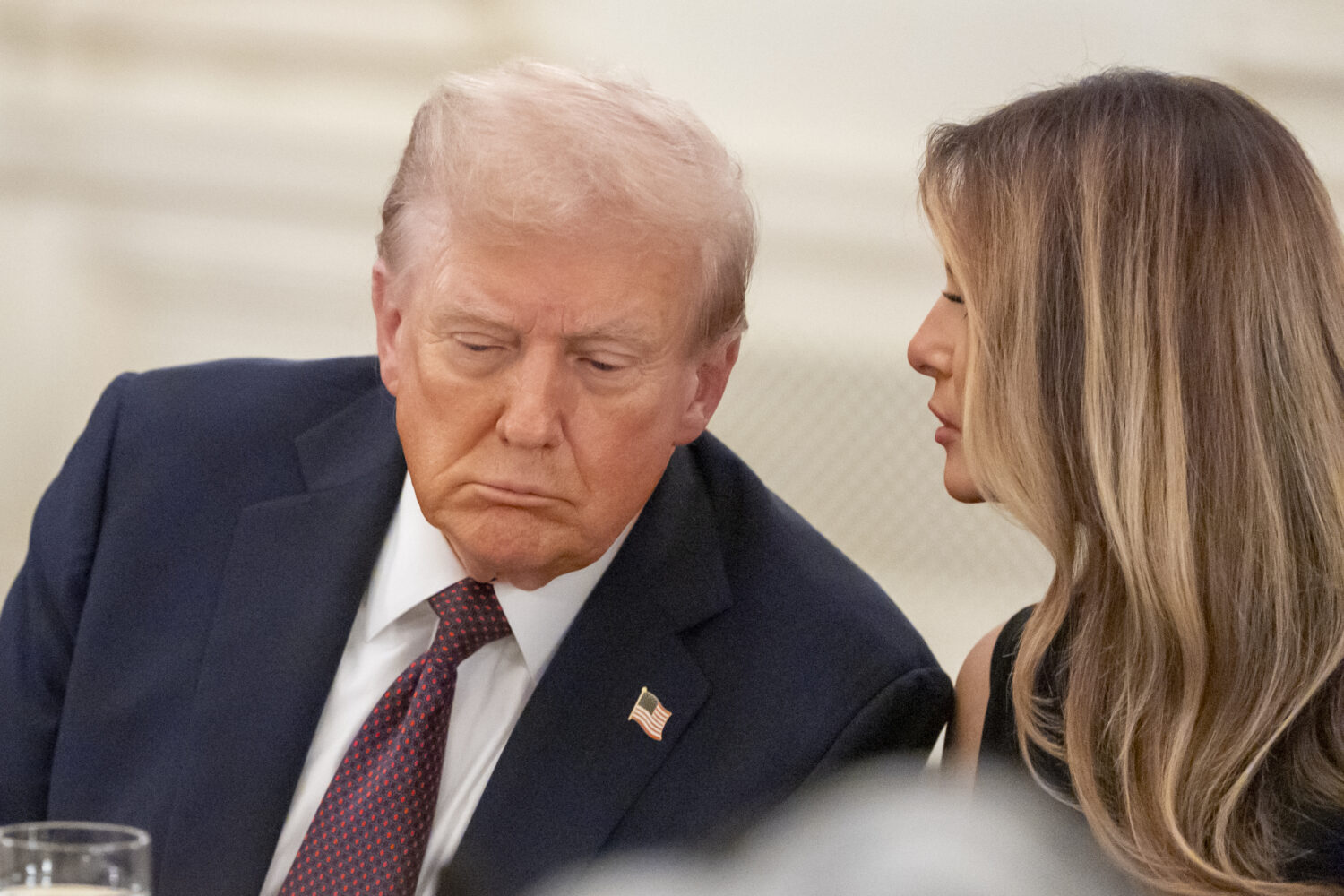 President Donald Trump listens as first lady Melania Trump repeats a question for him during a dinn...